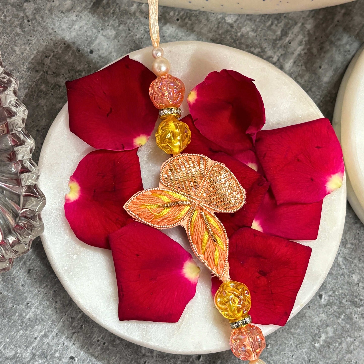 Designer Butterfly Rakhi with Latkan Rakhi for Bhaiya Bhabhi on a marble plate with rose petals