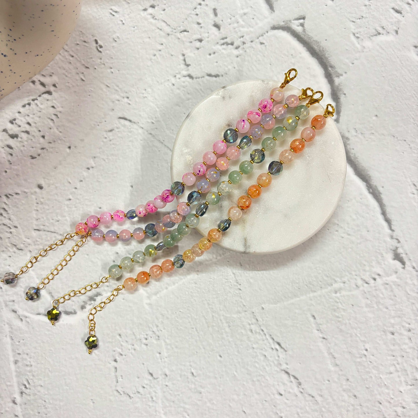 Colorful Marble Effect Beaded Bracelet Combo displayed on a marble coaster